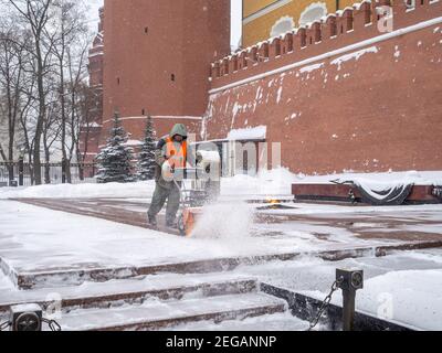 Moskau. Russland. Februar 12, 2021. Ein Hausangestellter reinigt Schnee mit einem Schneepflug am Grab des unbekannten Soldaten im Kreml während eines Schneefalls Stockfoto