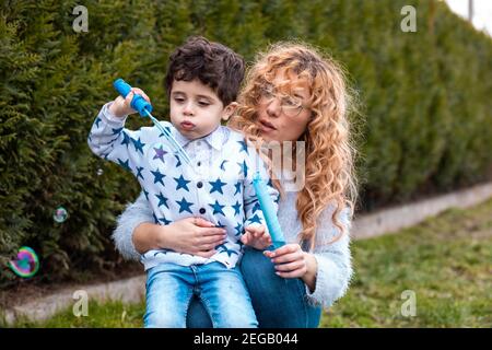 Mama spielt mit ihrem kleinen Jungen im Freien. Machen Seifenblasen mit Blasen kleben Stockfoto