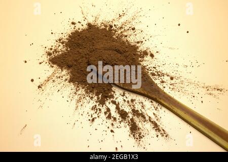 Ein Holzlöffel mit reinem entfatttem Kakaopulver auf Braun Hintergrund Stockfoto
