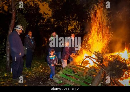 Menschen stehen um ein Lagerfeuer in Sunnyside Gardens, einem Gemeinschaftsgarten in Islington, an Halloween, London, Großbritannien Stockfoto