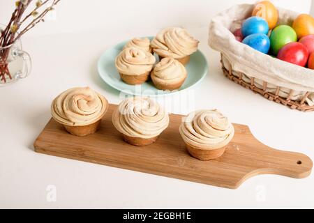 Cruffins osterfrühlingsgebäck, eine Mischung aus Muffin und Croissant auf einem hellen Hintergrund, die Komposition Ostern bemalte Eier Weide und Kuchen. Stockfoto