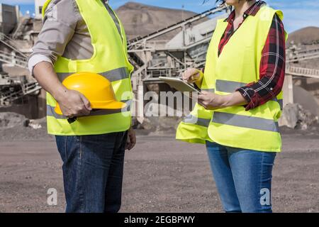 Seitenansicht der Ernte anonyme Architektin mit Tablet und Kommunikation mit männlichen Kollegen während des Treffens über Industriebau Standort Stockfoto