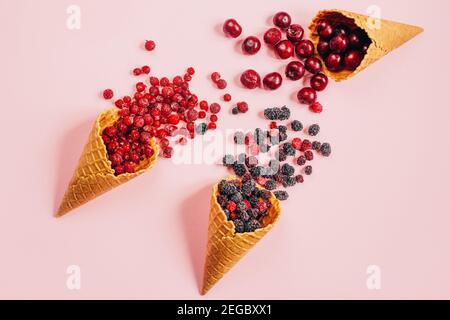 Draufsicht auf Beeren Kirsche Johannisbeere Maulbeere in Waffelbecher Auf rosa Hintergrund Stockfoto