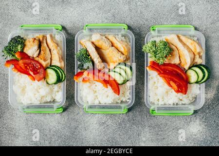 Draufsicht auf Lunchboxen mit Lebensmitteln Reis Fleisch Gemüse Und Früchte auf grauem Hintergrund zentriert Stockfoto