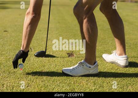 Kaukasischer älterer Mann, der einen Golfball auf dem Grün platziert Stockfoto