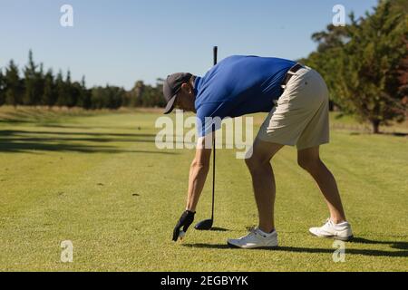 Kaukasischer älterer Mann, der einen Golfball auf dem Grün platziert Stockfoto