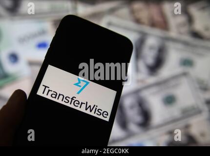 Viersen, Deutschland - Februar 9. 2020: Nahaufnahme des Smartphone-Bildschirms mit Logo-Schriftzug des Online-Geldtransferdienstes transferwise, verschwommene Banknoten Stockfoto