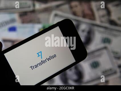 Viersen, Deutschland - Februar 9. 2020: Nahaufnahme des Smartphone-Bildschirms mit Logo-Schriftzug des Online-Geldtransferdienstes transferwise, verschwommene Banknoten Stockfoto