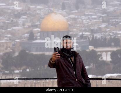 Jerusalem, Israel. Februar 2021, 18th. Ein Palästinenser macht am Donnerstag, den 18. Februar 2021, ein Selfie mit Blick auf den Schnee auf dem Felsendom im Al Aqsa-Moschee-Gelände in der Altstadt Jerusalems. Foto von Debbie Hill/UPI Kredit: UPI/Alamy Live Nachrichten Stockfoto