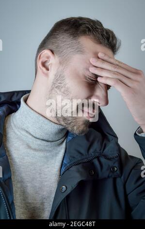 Porträt eines jungen Mannes, der seine Stirn berührt, um sich zu fokussieren Oder wegen Kopfschmerzen Stockfoto