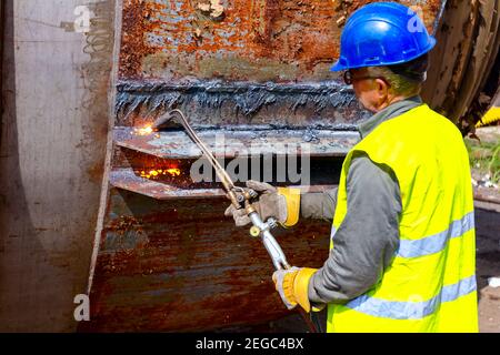 Worker ist Schneiden Manuell alte Metall Bau mit Gas Gemisch aus Sauerstoff und Acetylen, Propan. Stockfoto