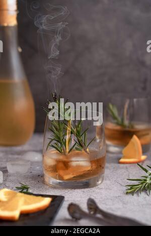 Alkoholisches Getränk mit Orangenscheiben und dampfendem Rosmarin Stockfoto