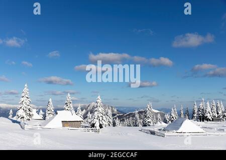 Idyllische alte Holzhütte mit Schnee bedeckt in der Berglandschaft des beliebten Wanderziels Velika planina, Slowenien Stockfoto