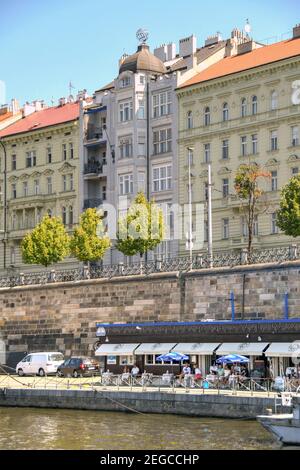 Prag, Tschechische Republik - Juli 2018: Menschen, die vor einem Café am Flussufer am Ufer der Moldau in Prag sitzen Stockfoto