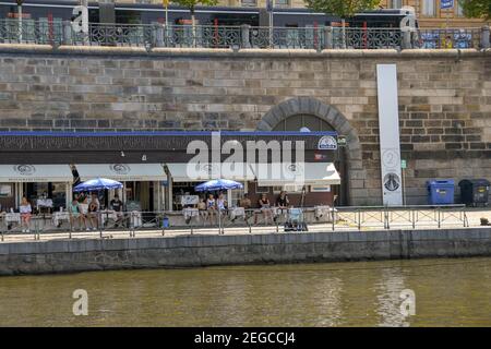 Prag, Tschechische Republik - Juli 2018: Menschen, die vor einem Café am Flussufer am Ufer der Moldau in Prag sitzen Stockfoto