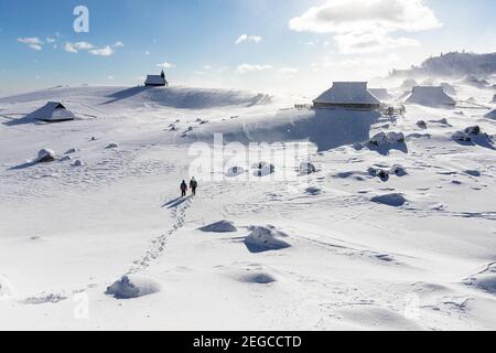 Mutter und Sohn wandern zur Kapelle der Schneemarie bei windigen Bedingungen auf der Velika planina Wiese, Slowenien Stockfoto