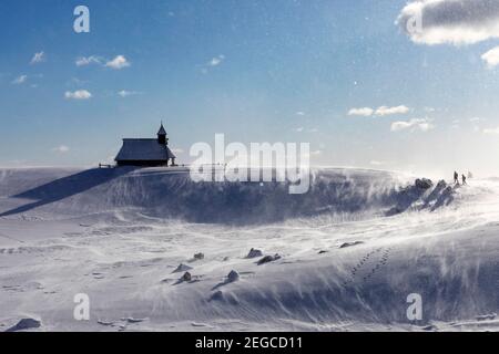 Mutter und Sohn wandern zur Kapelle der Schneemarie bei windigen Bedingungen auf der Velika planina Wiese, Slowenien Stockfoto