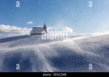 Kapelle der Schneemarie bei windigen Bedingungen auf der Velika planina Wiese, Slowenien Stockfoto