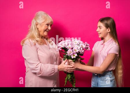 Enkelkind präsentiert Blumen zu Oma zu Hause, glückliche häusliche Momente - Familie Spaß, Konzepte über ältere Menschen, Multi-Generation-Familie und r Stockfoto