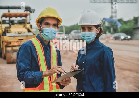 Arbeiter Techniker Tragen Sie eine Maske, die auf der Straße vor Ort mit einem Tablet arbeitet Konstruktion Stockfoto