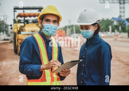 Arbeiter Techniker Tragen Sie eine Maske, die auf der Straße vor Ort mit einem Tablet arbeitet Konstruktion Stockfoto