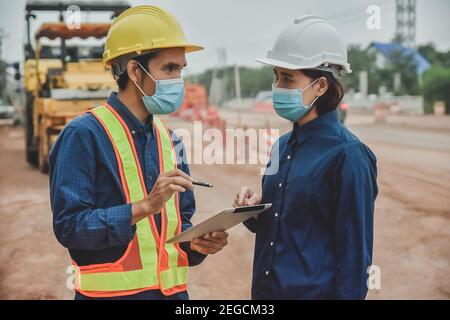 Arbeiter Techniker Tragen Sie eine Maske, die auf der Straße vor Ort mit einem Tablet arbeitet Konstruktion Stockfoto