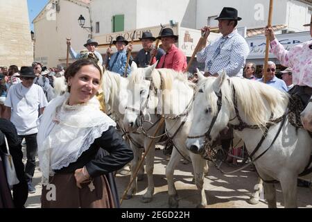 Frankreich Saintes Maries De La Mer 'Les Gardiens Camargaises', auf ihren Camargue-Pferden, und eine einheimische Frau in traditioneller Artesianer-Tracht warten draußen Stockfoto