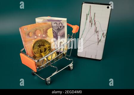 Bitcoin mit Pfund und Euro-Bargeld im Einkaufswagen Stockfoto