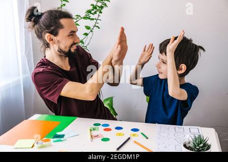 Glücklicher Autismus Junge während der Therapie mit Schullehrer, Lernen und Spaß zusammen Stockfoto