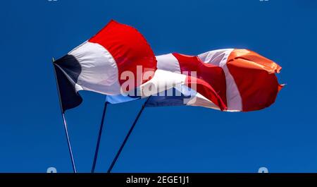 Nahaufnahme von wackenden Flaggen von Frankreich auf Pole unter einem klaren blauen Himmel Stockfoto