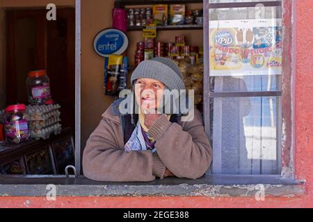 Ältere bolivianische Frau, Verkäuferin, die durch das Schaufenster in der Stadt Uyuni, Provinz Antonio Quijarro, Abteilung Potosí, Bolivien schaut Stockfoto