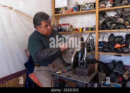 Altmodischer bolivianischer Schuhmacher mit alten Nähmaschinen, die Schuhe ausbessern, am Marktstand in der Stadt Uyuni, Provinz Antonio Quijarro, Potosí, Bolivien Stockfoto