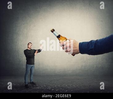 Aufhören zu konsumieren Alkohol Konzept. Der Mensch weigert sich, eine Flasche Bier aus einer riesigen Hand zu nehmen, als Metapher für Sieg gegen sucht. Kerl lehnen trinken alc Stockfoto