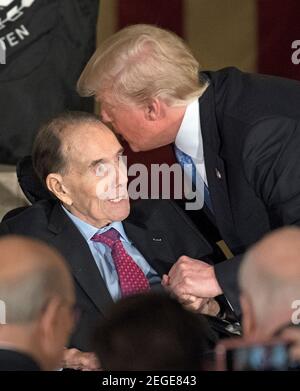 FILEBILDER: US-Präsident Donald J. Trump pflanzt einen Kuss auf die Stirn des ehemaligen US-Senators Bob Dole (Republikaner von Kansas), als er am Mittwoch, dem 17. Januar 2017, in der Rotunde des US-Kapitols an einer Goldmedaillenzeremonie im Kongress zu Ehren von Dole teilnimmt. Der Kongress hat Goldmedaillen als höchsten Ausdruck nationaler Wertschätzung für herausragende Leistungen und Beiträge in Auftrag gegeben. Dole diente im Kongress von 1961 bis 1996, war der Senat GOP Führer von 1985 bis 1996, und war der 1996 republikanische Partei Nominee für Präsident der Vereinigten Staaten.Kredit: Ron Sachs/CNP Stockfoto
