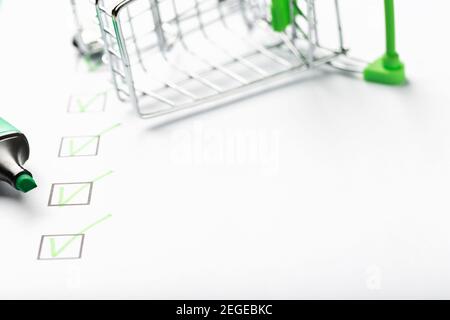 Supermarkt Warenkorb und grüne Markierung auf der Checkliste markiert. Einkaufscheckliste abgeschlossenes Aufgabenkonzept. Stockfoto