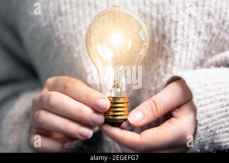 Weibliche Hand hält eine glänzende Glühbirne, große Idee, Innovation und Inspiration, Geschäftskonzept Hintergrund Stockfoto