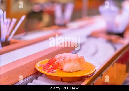 Nahaufnahme auf einem Teller, der zwei frische Shrimps-Sushi auf der Rolle eines Sushi-Förderbands oder des Kaiten-zushi-Restaurants in Japan trägt. Stockfoto