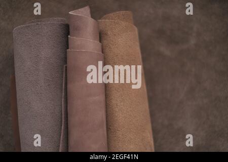 Braune Echtlederrolle.echtes Leder-Set. Leder in Rollen auf einer braunen Lederoberfläche.Hobby und Handwerk Material. Leder Textur.Material für Schuhe Stockfoto