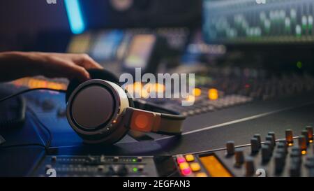 Nahaufnahme eines Kopfhörers, der im Music Recording Studio auf dem Mischpult liegt. Erfolgreiche Toningenieurin Kreiert Modern Song. Stockfoto