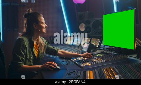 Portrait der stilvollen weiblichen Audio Engineer Producer arbeitet in Music Record Studio, verwendet Green Screen Computer Display, Mixer Board, Control Desk Stockfoto