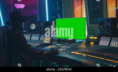 Stilvoller Audio Engineer Producer, der in Music Record Studio arbeitet, verwendet Chroma Key Computer Display, Mixer Board Equalizer und Control Desk Stockfoto