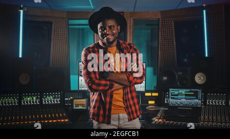 Portrait des jungen schwarzen Künstlers, Musikers, Toningenieurs, Produzenten mit stilvollem Hut und Standing im Music Record Studio. In der Hintergrundsteuerung Stockfoto