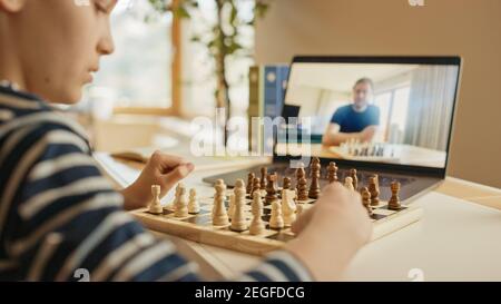 Brillanter kleiner Junge, der Schach mit seinem entfernten Verwandten oder Onkel spielt, verwendet Laptop für Videoanruf. Remote Online Education, E-Education, Kommunikation Stockfoto