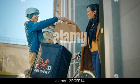 Happy Food Delivery Mann trägt thermischen Rucksack auf einem Fahrrad liefert Restaurant Bestellung an eine schöne weibliche Kunden. Kurier Liefert Takeaway Lunch Stockfoto