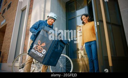 Happy Food Delivery Mann trägt thermischen Rucksack auf einem Fahrrad liefert Restaurant Bestellung an eine schöne weibliche Kunden. Kurier Liefert Takeaway Lunch Stockfoto