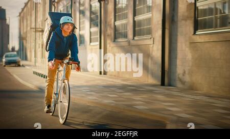 Happy Food Delivery Kurier Tragen Thermal Rucksack fährt ein Fahrrad auf der Straße, um Aufträge für Kunden und Kunden zu liefern. Sonniger Tag in der modernen Stadt Stockfoto