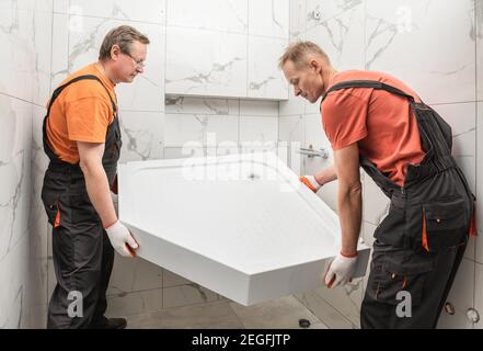 Arbeiter installieren eine Duschwanne im Badezimmer. Stockfoto