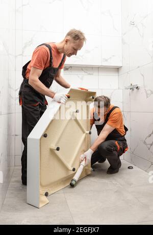 Arbeiter installieren eine Duschwanne im Badezimmer. Stockfoto