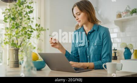 Junge attraktive Frau mit Laptop-Computer für die Zahlung für Shopping oder Service mit einer Kreditkarte im Internet. Weibliche sitzen in einem modernen gemütlich Stockfoto