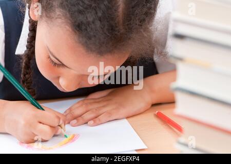 Schwarz gemischt Rasse biracial afroamerikanischen Mädchen Kind schulmädchen in Klassenzimmer zeichnen einen Regenbogen Stockfoto